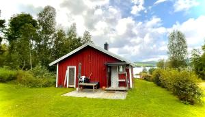 a red shed with a dog sitting on a bench in front at Hemsö Hideaway in Kojbacken