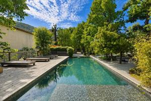 a swimming pool with benches and a wooden deck at Château De Jouques in Gémenos