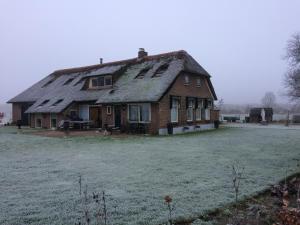 een oud huis met een rieten dak op een veld bij B&B op Wijngoed Havelte in Havelte