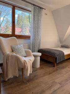 a bedroom with a bed and a chair and a window at Apartament u SKOCZKA in Poronin