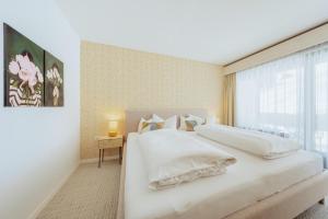 a bedroom with a large white bed and a window at Apartment Hotel Pfeifer in Gaschurn +58 photos