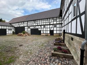 a large black and white building with a courtyard at Zirkuswagen im Gutshof in Lutterberg