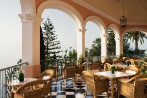 a restaurant with tables and chairs on a balcony at Reid's Palace, A Belmond Hotel, Madeira in Funchal
