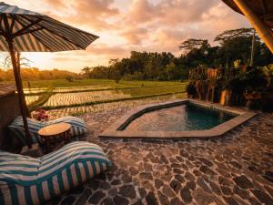 a pool with chairs and an umbrella on a patio at Uma D Mapad Sidemen in Sidemen +47 photos