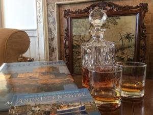 a bottle of whiskey and a book on a table at Arduthie House in Stonehaven