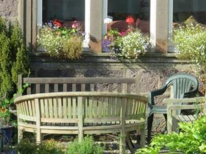 a wooden bench in front of a window with flowers at Arduthie House in Stonehaven