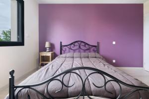 a bed in a bedroom with a purple wall at Maison Peyrelade in Coulounieix-Chamiers +23 photos