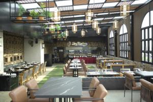 a dining room with tables and chairs and windows at Avinash International in Jagdalpur