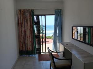 a room with a desk and a view of the ocean at Galene Guest House in Port Shepstone