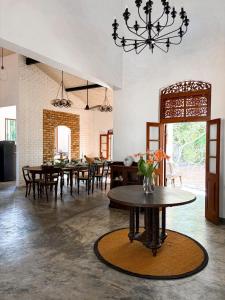 a dining room with a table and chairs and a chandelier at The Surveyor's Bungalow in Udugampola