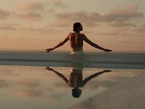 a woman standing on the beach with her reflection in the water at Aguas de Ibiza by NCalma Hotels in Santa Eularia des Riu