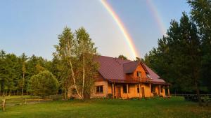 a rainbow over a wooden house with at Na Wysokiej Górce- Agroturystyka in Grabowiec