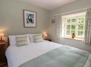 a bedroom with a white bed with two pillows and a window at Tyn Y Fron in Llanrhystyd