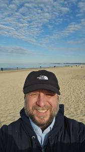 a man wearing a hat on the beach at Michal in Tleń