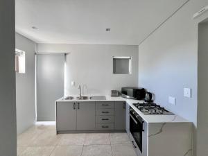 a white kitchen with a stove and a sink at Blouberg Village Place in Cape Town