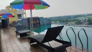 a balcony with chairs and umbrellas next to a swimming pool at Avinash International in Jagdalpur
