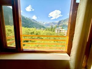 a window with a view of a mountain at The Cow Boy Manali in Manāli