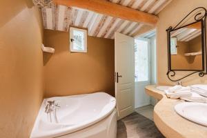 a bathroom with a tub and two sinks and a mirror at Hôtel Le Rocher des Abeilles in Saint-Martin-de-Castillon