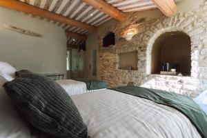 a bedroom with two beds and a stone wall at Hôtel Le Rocher des Abeilles in Saint-Martin-de-Castillon +17 photos