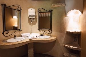 a bathroom with two sinks and a mirror at Hôtel Le Rocher des Abeilles in Saint-Martin-de-Castillon