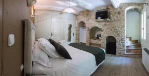 a bedroom with a large bed and a stone wall at Hôtel Le Rocher des Abeilles in Saint-Martin-de-Castillon