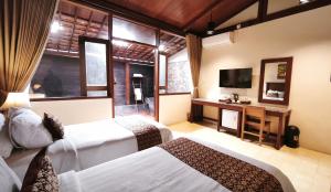 a hotel room with two beds and a television at DAMAI in Canggu