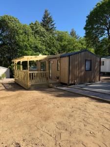 a wooden cabin with a porch in a dirt lot at Bahia in Le Faulq