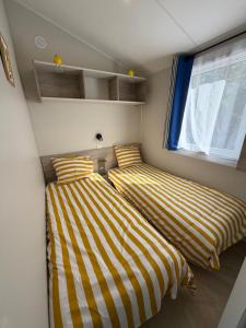 two beds in a small room with a window at Bahia in Le Faulq