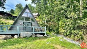 a small house with a blue deck in the grass at Serene Mountain Waterfront A-Frame Cabin in Robbinsville