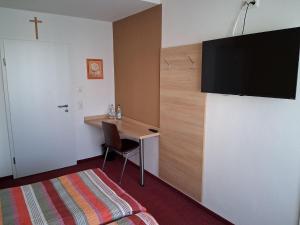 a hotel room with a desk and a tv on a wall at Pension Hösl in Mitterteich