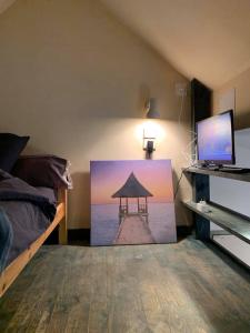 a bedroom with a painting of a pier on the wall at Près de l'aéroport in Ossun