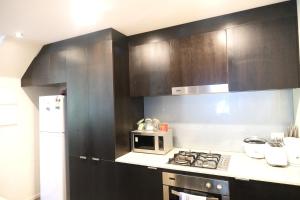 a kitchen with black cabinets and a white microwave at Docklands Serenity in Melbourne
