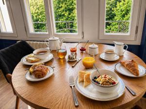 a wooden table with plates of breakfast food on it at Le Petit Jard'Inn in Chalons en Champagne