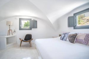 a white bedroom with a bed and a chair at Lagadi Suites Mesaria in Mesaria +45 photos