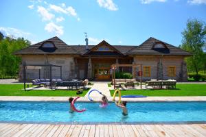 three girls playing in a pool in front of a house at Ułańska Zagroda in Człopa
