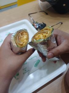 a person holding two wrapped food items on a tray at Harshil Pinewood Homestay in Harsil