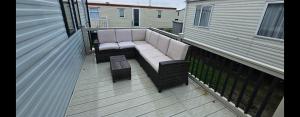 a balcony with a couch on a deck at Sam's Caravan Hire Coastfield Holiday Village Ingoldmells in Ingoldmells
