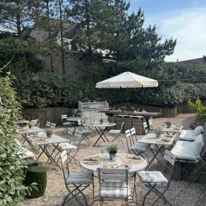 a patio with tables and chairs and an umbrella at Hotel Zonne in Noordwijk aan Zee