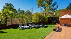 a group of chairs and an umbrella on a lawn at Villa Sitges Maria Sunny Oriented SW AC Confortable High Quality 5 star guest coments in Olivella