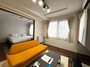 ein Wohnzimmer mit einem gelben Sofa und einem Bett in der Unterkunft ハミルトンイースト in Sapporo