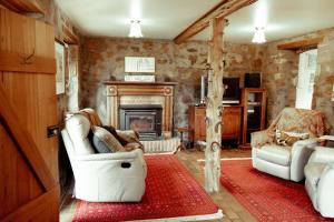 a living room with two chairs and a fireplace at Blacksmith's Cottage at Lisdillon Estate in Little Swanport