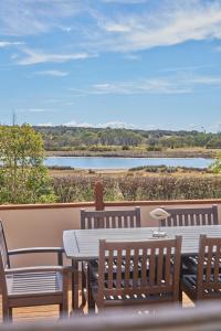 a table and chairs on a deck with a view of a river at Blacksmith's Cottage at Lisdillon Estate in Little Swanport