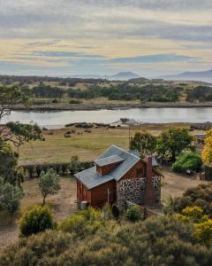 an old house on a hill with a lake in the background at Blacksmith's Cottage at Lisdillon Estate in Little Swanport +60 photos