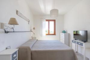 a white bedroom with a bed and a television at Casa Martina by ElbaSummer in Lacona