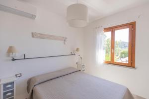 a white bedroom with a bed and a window at Casa Martina by ElbaSummer in Lacona