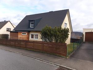 a house with a black roof and a wooden fence at Zimmervermietung Müller in Kelheim
