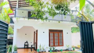 a white house with a red door and a balcony at Chami Leisure Home in Talpe