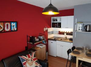 a kitchen with red walls and a couch and a table at Studio 4 pers pieds des pistes Piau-engaly in Aragnouet