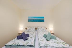 a bedroom with two beds with pillows and a painting at Seaview apartments Refugium Krk in Polje