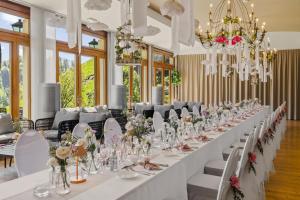 a long table in a room with white chairs and flowers at Le Saint Georges in Gruyères